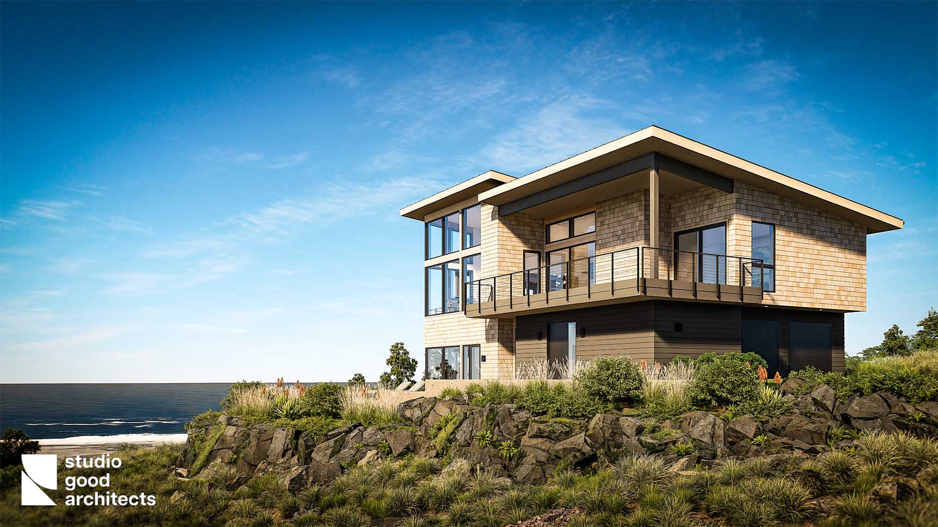 Modern coastal house design by Studio Good Architects, featuring large windows, a balcony, and natural stone landscaping against a clear blue sky.